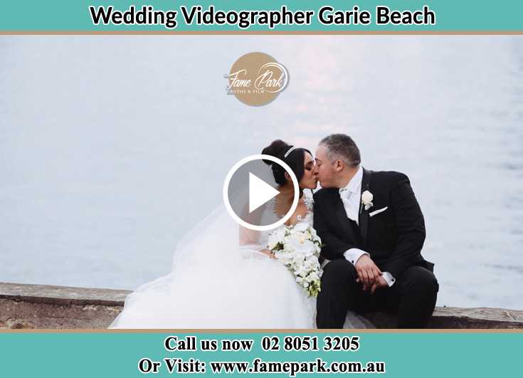 Bride and Groom kissed at the shore while sitting Garie Beach NSW 2233